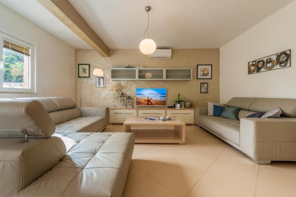 Spacious lounge with two leather sofas and a TV